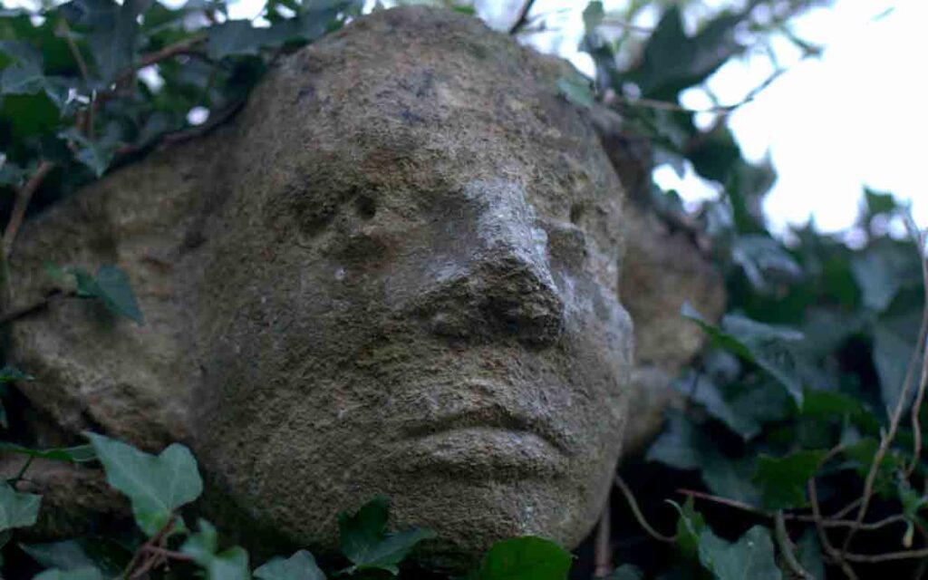 The carved stone head looking over Olney Churchyard