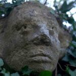 The carved stone head looking over Olney Churchyard