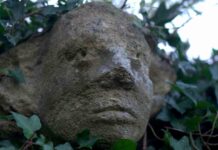 The carved stone head looking over Olney Churchyard