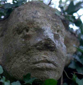 The carved stone head looking over Olney Churchyard