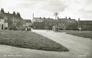 Historical image showing The Green at Atwick, the stone cross on the left of the image is said to be haunted by a strange white lady. 