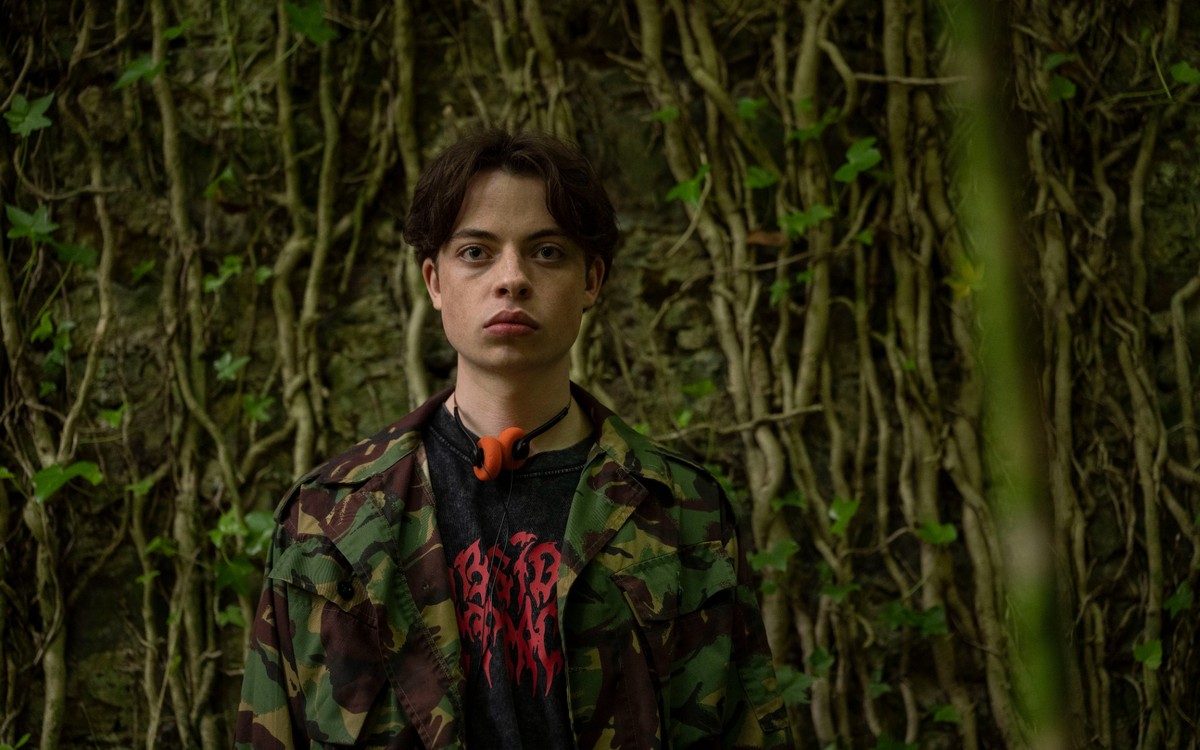 BBC confirms The Witch Farm release date 3 Lewin Lloyd as Jonathan stands among trees with orange headphones around his neck.